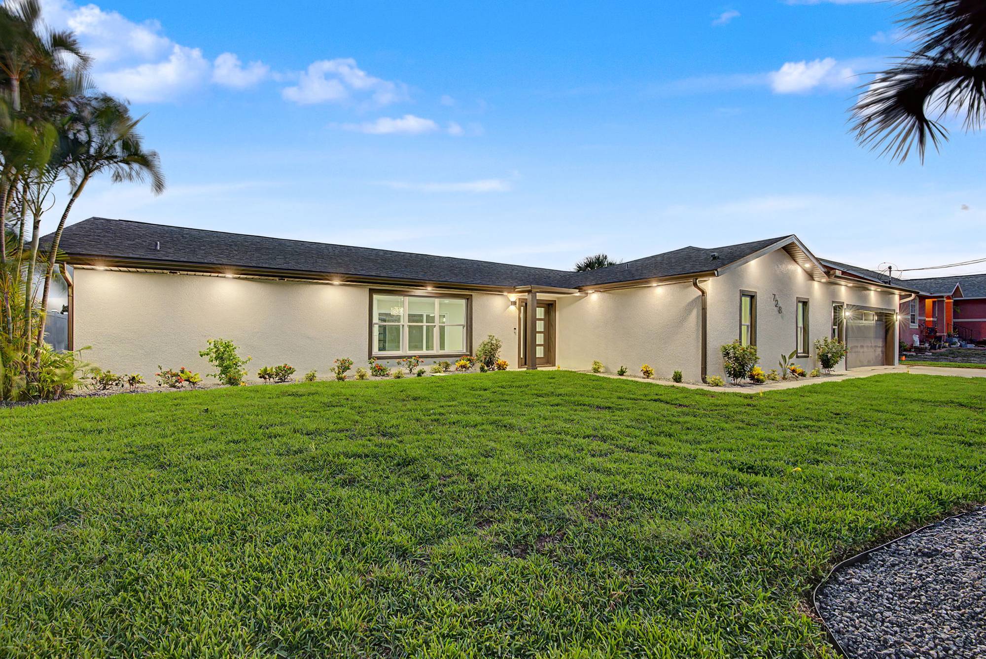 Single-story home with exterior lights on at dusk