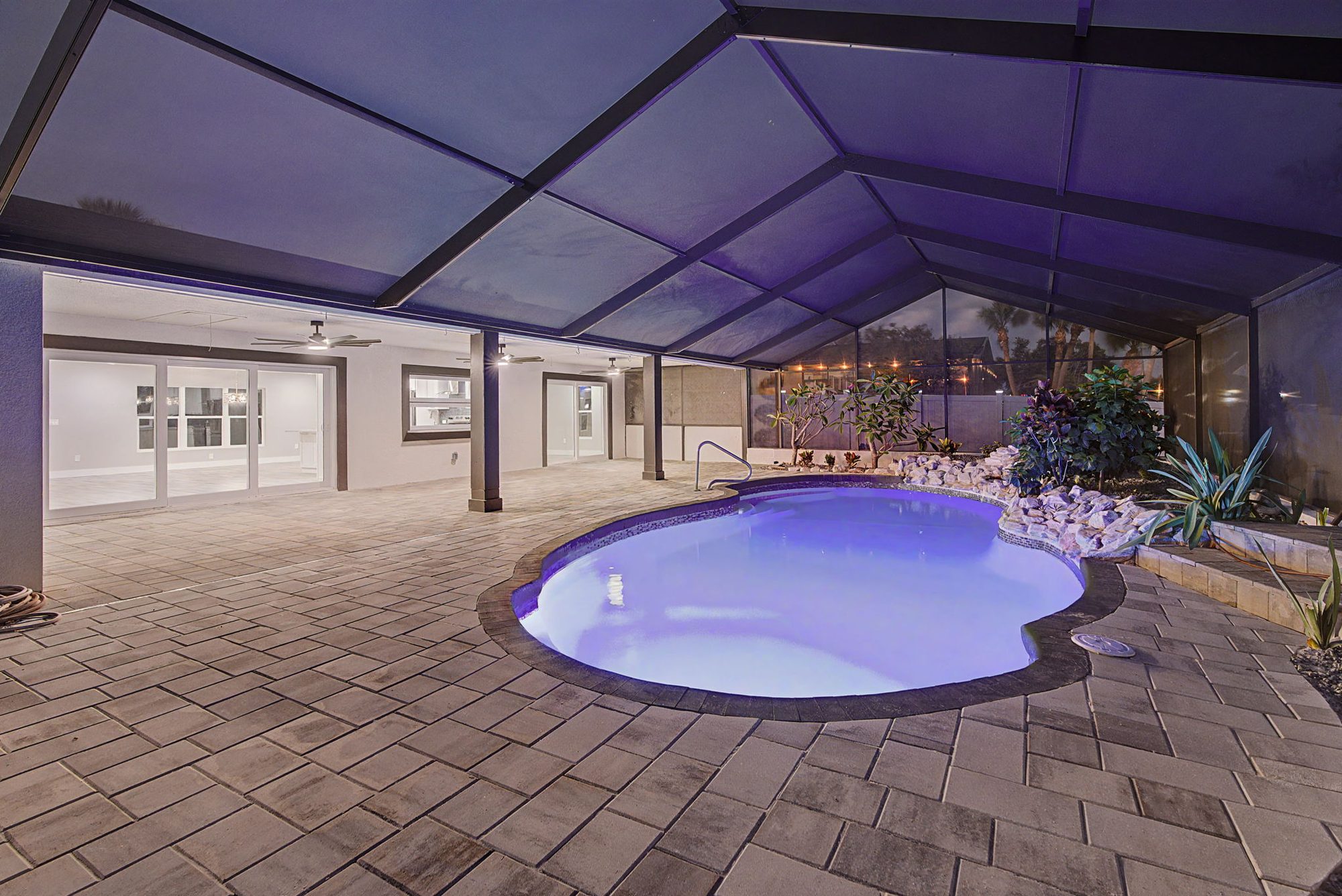 Lit pool under a covered lanai at twilight